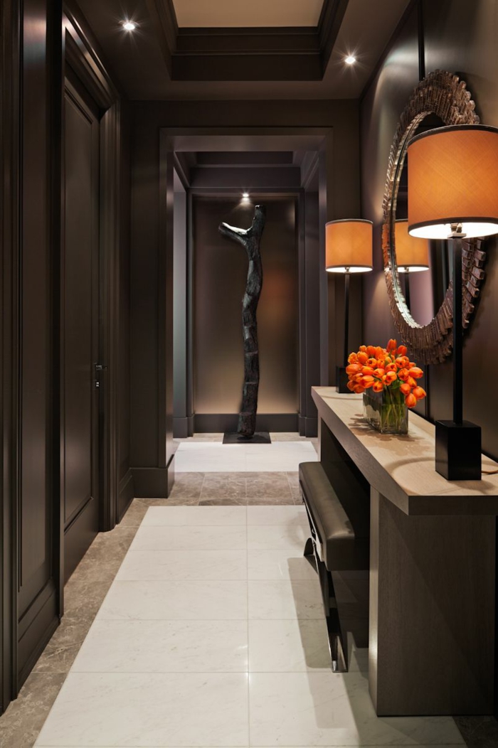couloir long, console d'entrée imposante, miroir rond encadré, sculpture noire, lampes abat-jour