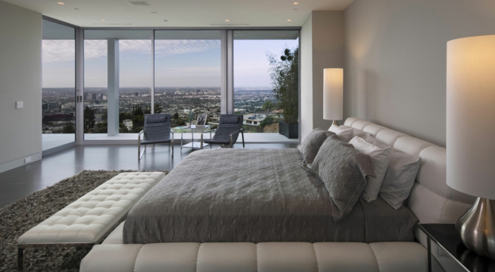 chambre de luxe avec vue, lampes cylindiques, banquette de lit blanche, tapis gris anthracite, murs gris