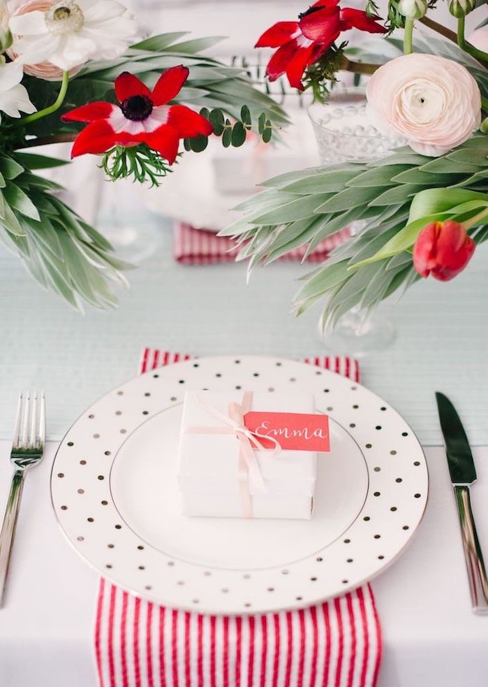 un petit cadeau surprise dans une boite blanche avec étiquette rose comme porte nom mariage, centre de table en bouquets de fleurs et serviettes à rayures