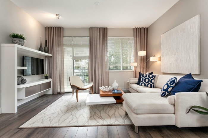 quelle deco moderne salon créer pour une habitation tendance, tapis blanc sur un plancher en bois, canapé blanc, coussins déco, meuble tv blanc