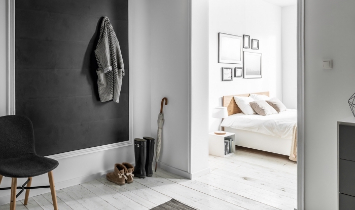esprit minimaliste dans un couloir et chambre à coucher aux murs blancs et parquet de bois clair avec pan de mur gris foncé