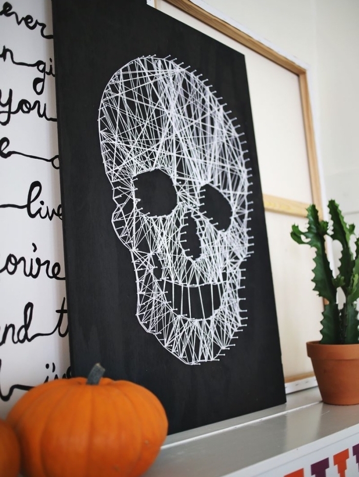 exemple de déco de Halloween DIY avec un tableau noir à fil blanc en forme de crâne et une petite citrouille orange