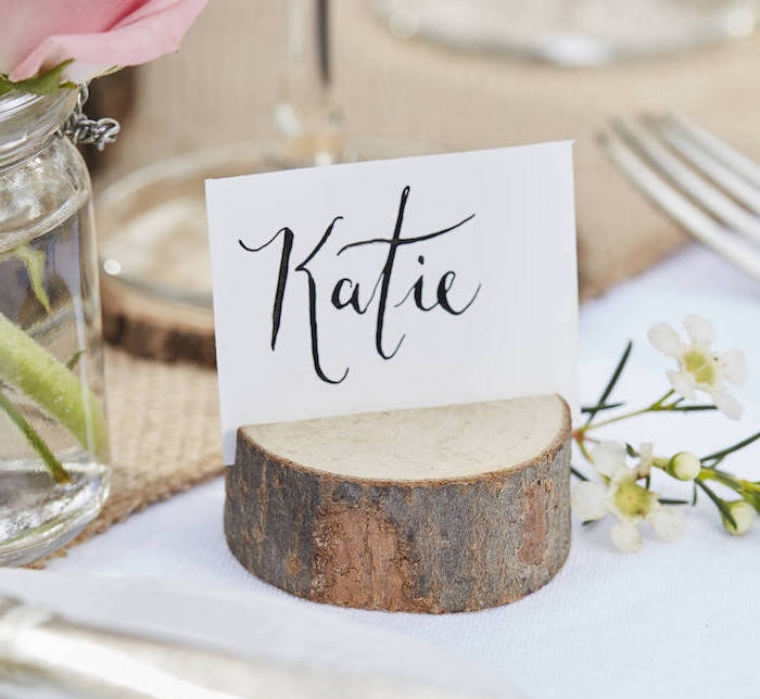 rondelle de bois incisé avec une étiquette nom invité sur un bout de carton blanc, chemin de table en jute