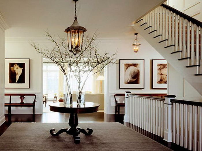 petite table ronde, tapis taupe, escalier avec rambarde blanche, luminaire lanterne, créer une entrée dans un espace ouvert