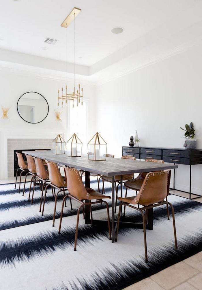 table à manger scandinave avec chaises en cuir marron rétro dans salle blanche sur tapis blanc noir