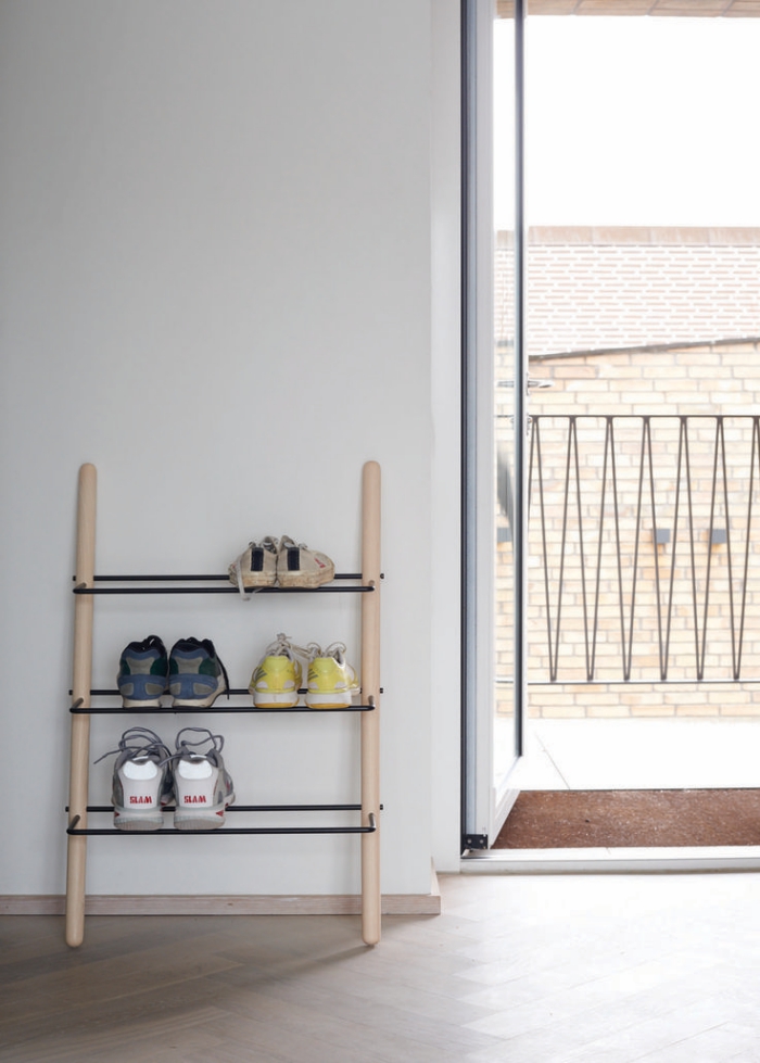 petit meuble chaussure d'esprit minimaliste scandinave en bois et métal, appuyé contre le mur