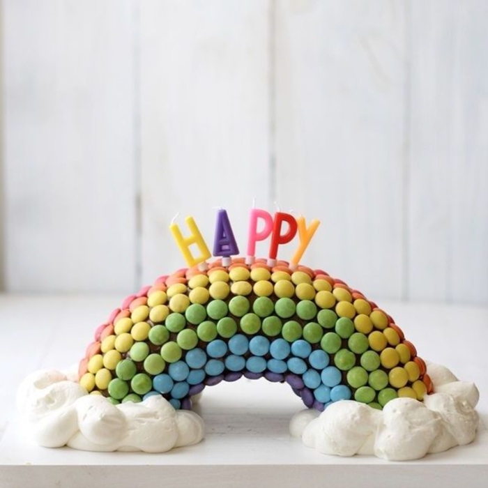 gateau au smarties multicolore en forme d'arc-en-ciel avec des nuages en crème chantilly, idée pour un gâteau d'anniversaire original à confectionner soi-même