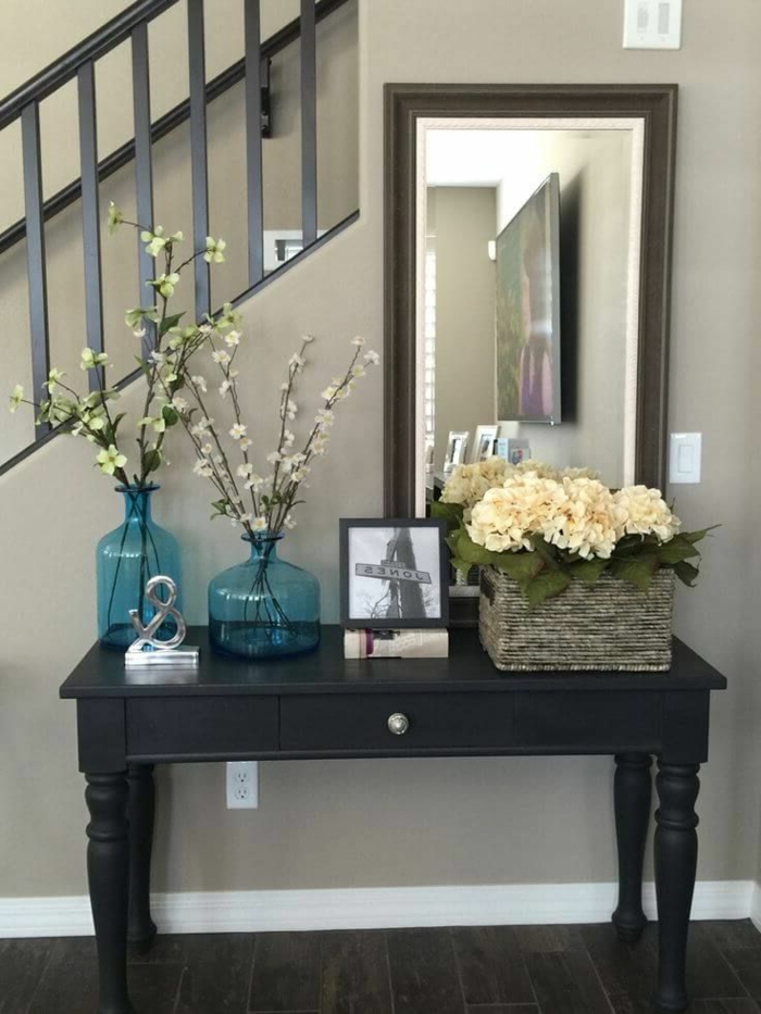 miroir rectangulaire, vases turquoises avec des tiges fleuries, bureau noir, panier rustique