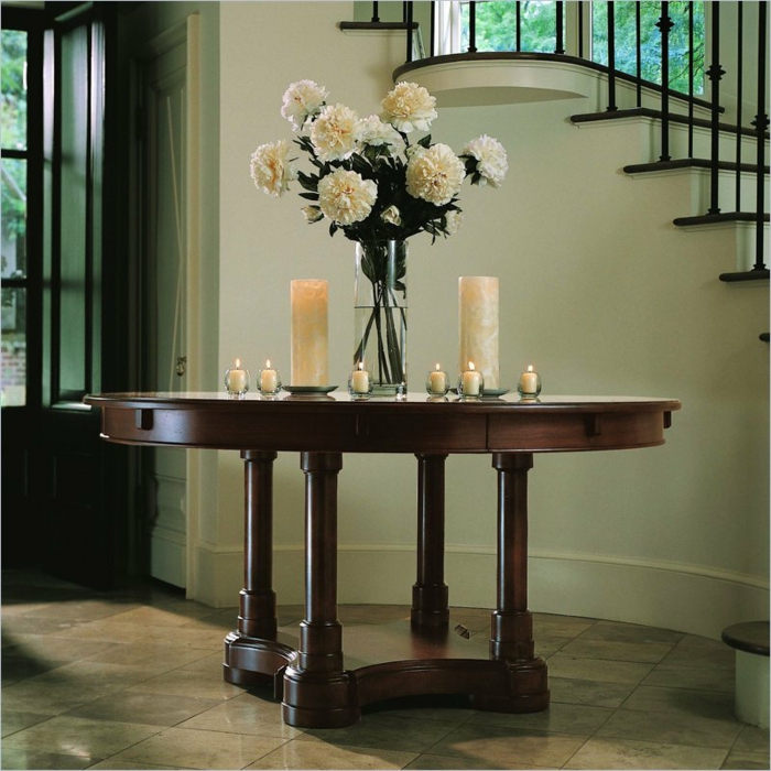 entrée simple et stylée, table en bois, bougies blanches, bouquet de pivoines près d'un escalier élégant