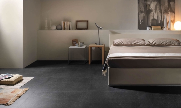 chambre à coucher large aux murs blancs avec sol gris anthracite, objets décoratifs à finition bois pour une ambiance cozy