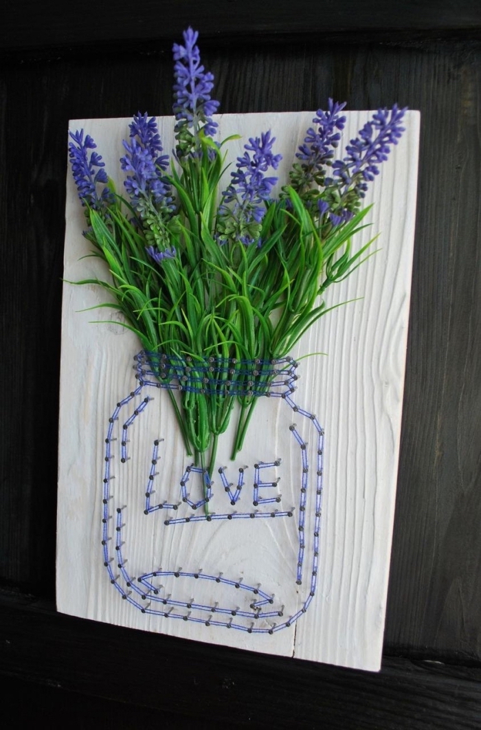 objet décoratif fait main avec planche de bois décoré avec fil violet en forme de bocal et un bouquet de fleurs violettes