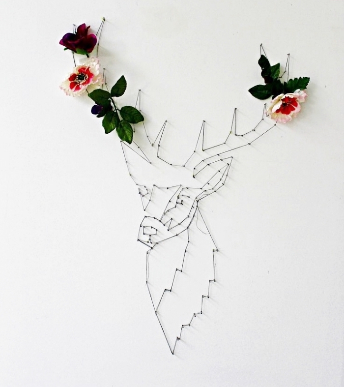 décoration murale de style minimaliste faite avec un gabarit fil tendu à design cerf blanc et noir avec cornes en fleurs