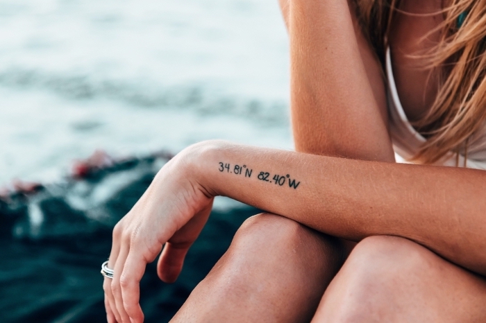 jeune femme au bord de la mer avec un tatouage original sur la main, modele tatouage en chiffres symbolique