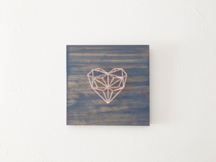 exemple de décoration murale dans le style minimaliste avec un coeur origami en fil blanc et rouge sur une planche de bois
