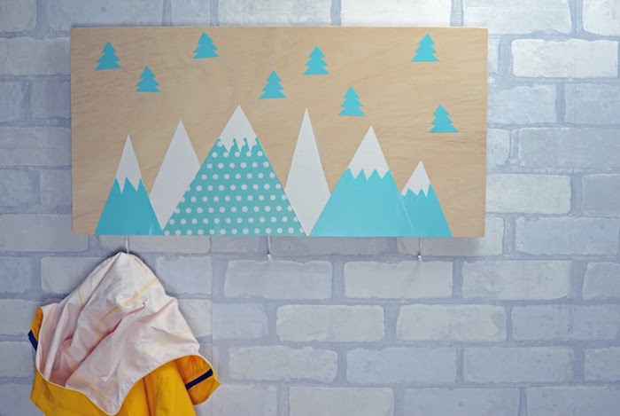 modele de porte manteau scandinave en planche de bois avec motif montagnes et sapins enneigés, mur de briques blanches, accroches simples