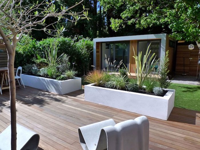 terrasse maison en bois composite, bacs à fleurs en béton blancs, fauteuils extérieur forme intéressante