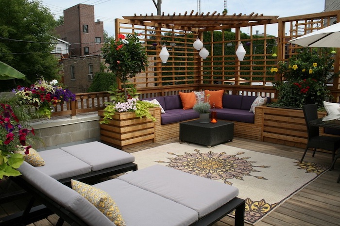 amenager une terrasse exterieure en bois, chaise longues, canapé bois avec une pergola bois, coussins d assise violets, fleurs en pots et bacs à fleurs