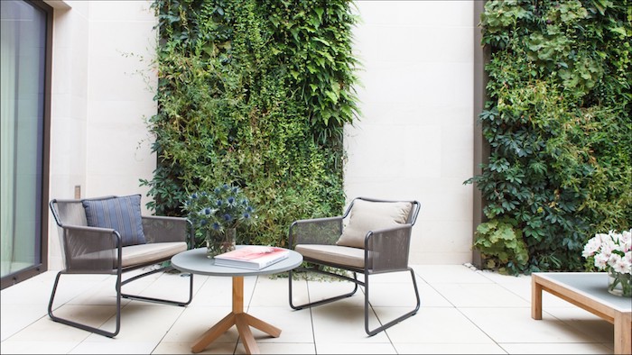 modele deco terrasse avec revetement en carreaux, table basse bois ronde, chaises metalliques, mur vegetal exterieur