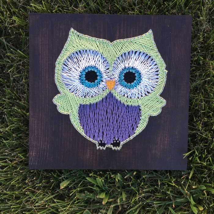 création mignonne sur une planche de bois foncé à design petit hibou vert et violet aux grands yeux bleus