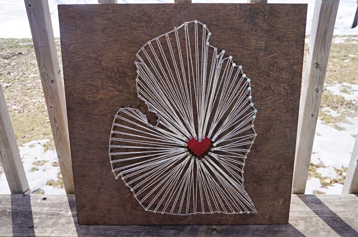 modèle de tableau en bois foncé avec création en fil blanc et petit coeur rouge au centre comme un objet DIY