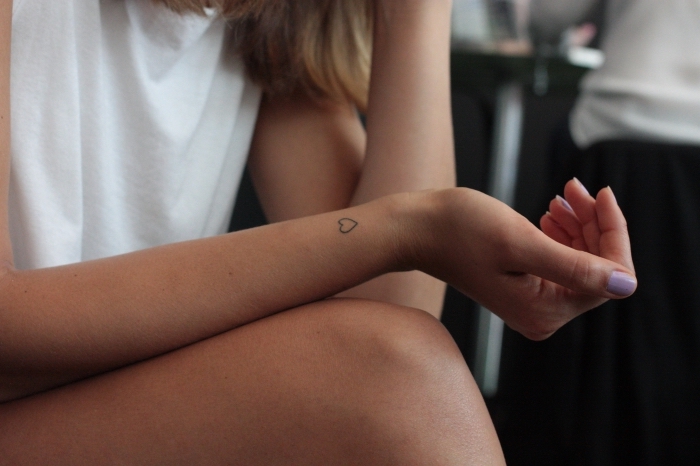 jolie variante de mini tattoo pour femme dans l'esprit romantique, petit coeur aux lignes et design simple tatoué sur le poignet