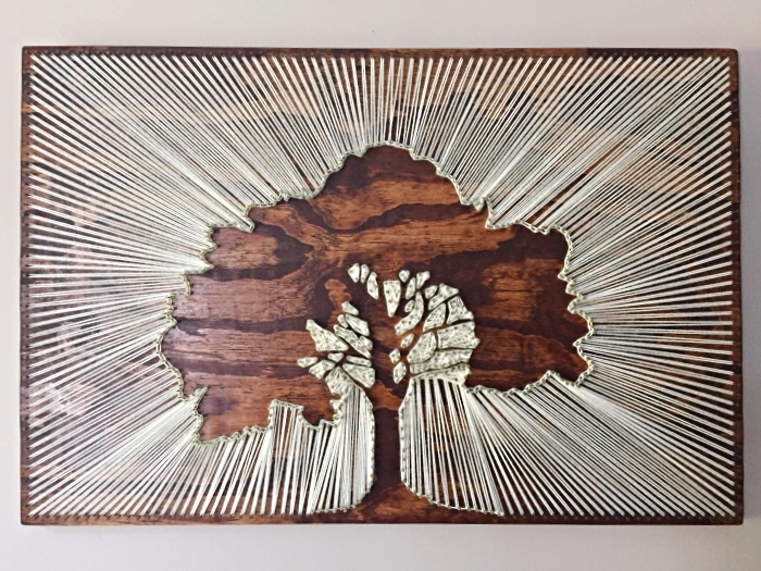 exemple de décoration murale DIY sur une planche de bois foncé à design arbre fabriqué avec fil et clous
