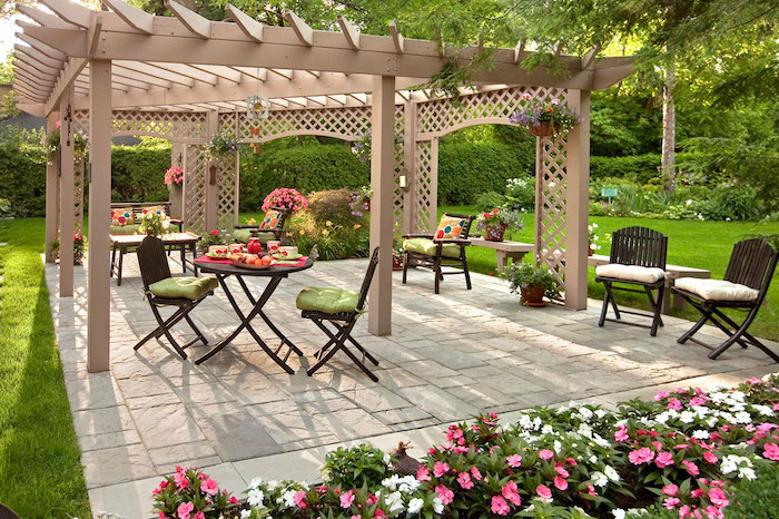 aménagement extérieur jardin terrasse avec des chaises et table bois, bordure de fleurs, gazon vert, pergola bois