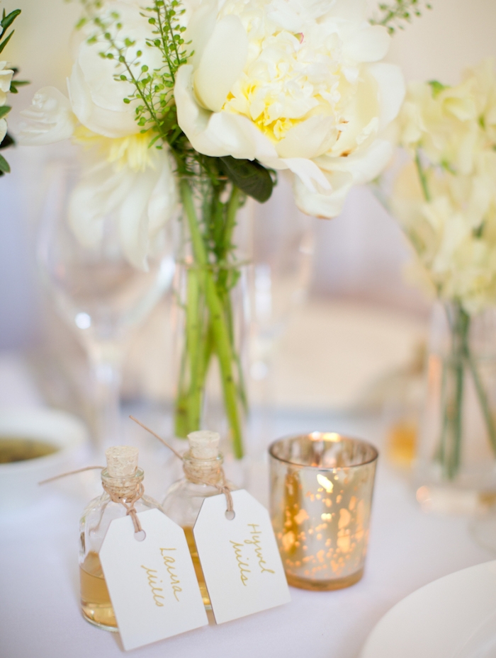 petites fioles remplies de boisson avec carton nom invité, centre de table en bouquets de fleurs dans un vase, bougeoirs diy