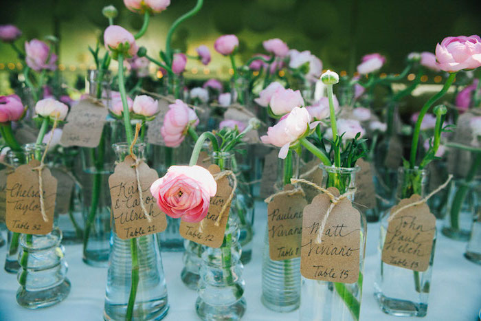 idée de petit soliflore en bouteille de verre avec une fleur dedans et carton papier kraft, numéro de table et nom invité