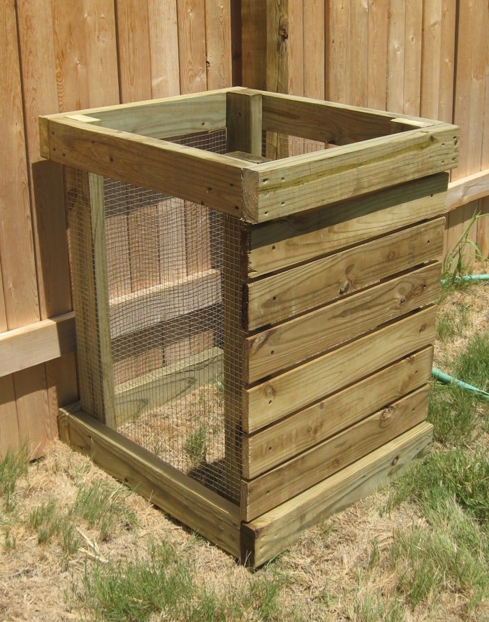 modèle de petit composteur de jardin fabriqué de planches de bois et grillage carré installé dans un coin de jardin