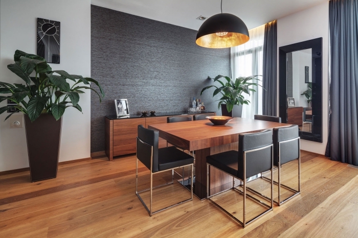 ambiance moderne et accueillante dans une salle à manger avec meubles de bois et décoration murale en peinture gris foncé