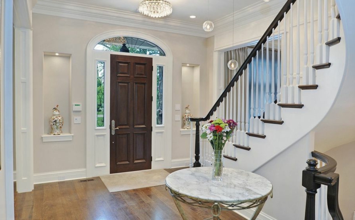 maison de luxe moderne, déco entrée maison, table ronde marbrée, porte d'entrée en bois foncé, escalier