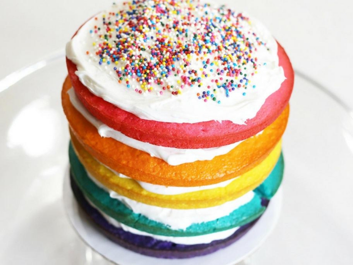 comment faire un gateau naked cake à plusieurs couches multicolore recouvertes de crème chantilly et décoré avec des perles en sucre colorées