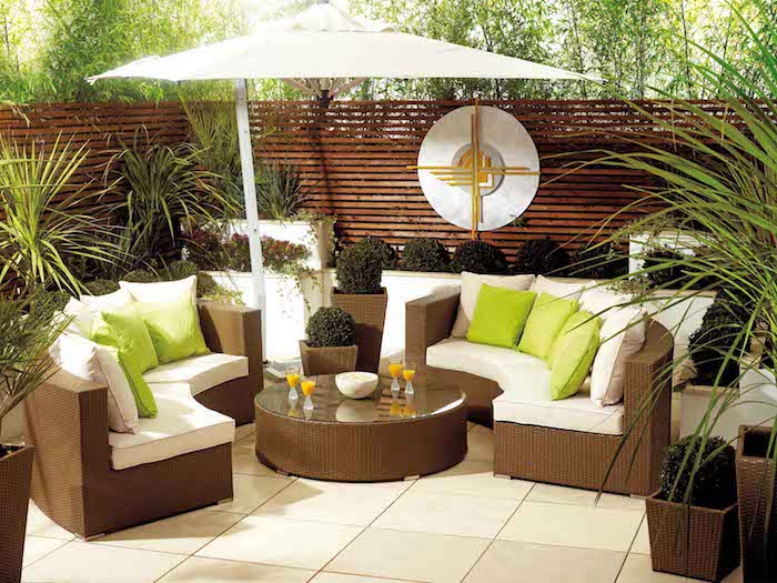 terrasse recouverte de carrelage canapés et table basse rotin, coussins d assise blancs et coussins décoratifs vert pistache, plantes en pots et bacs à fleurs, séparation en bois