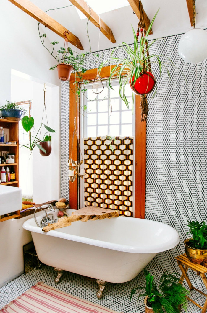 baignoire blanche vintage avec des pieds en métal couleur bronze, poutres en bois marron clair au plafond, style de bain bohème, plantes d'appartement, salle de bain verte 