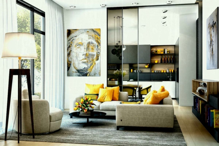 salon contemporain et gris et blanc, coussins jaunes, portrait art, grande lampe quatre pieds, verrière atelier donnant sur cuisine 