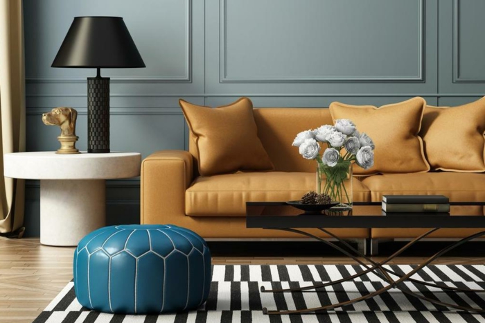 décoration intérieure salon, tapis rayé en noir et blanc, sofa moutarde, lampe blanche avec une grande table à abat-jour, panneaux muraux bleu canard