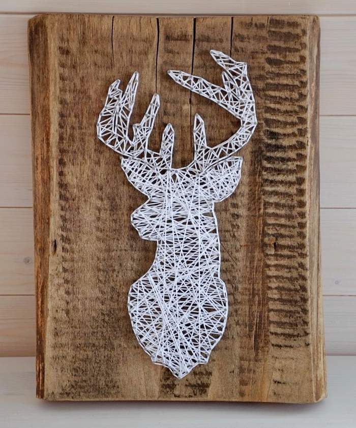 idée bricolage facile avec un panneau de bois massif décoré de fil blanc et de clous qui forme une tête de cerf
