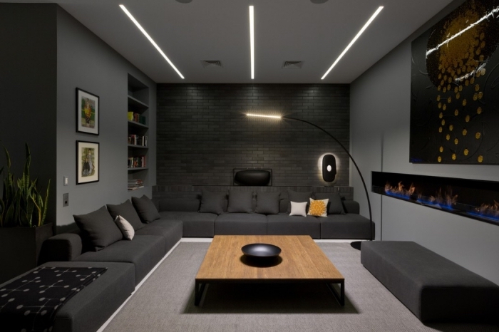 design intérieur en couleurs foncés dans l'esprit moderne avec un plafond blanc à éclairage neon blanc et pan de mur en pierre