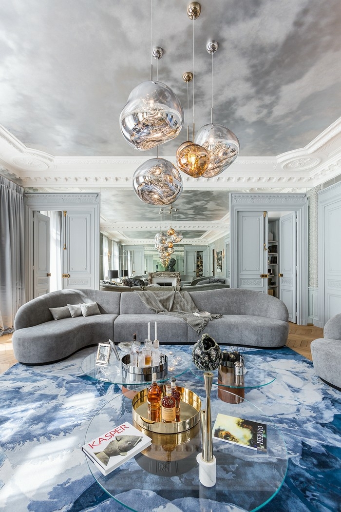 grand salon à déco grise, lampes pendantes, tables basses, tapis bleu, peinture du plafond originale