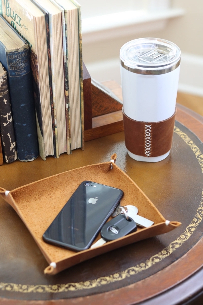 exemple rangement objets utile avec un support marron pour portable et clés sur une petite table ronde et foncée