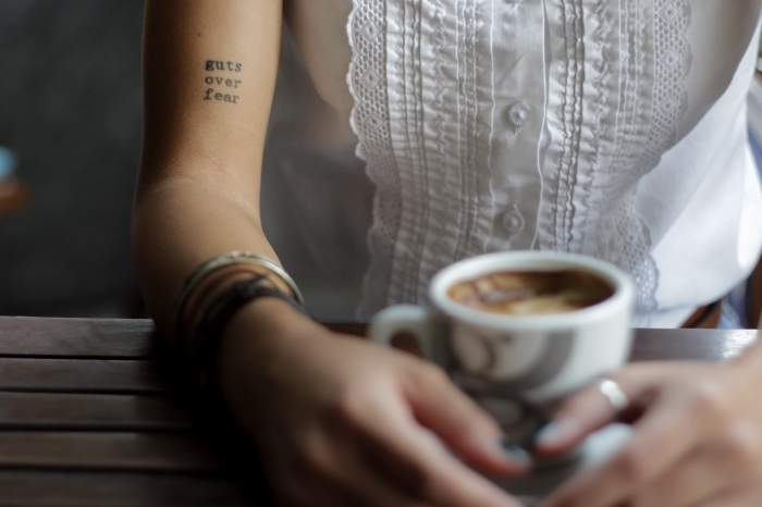 idée tatouage discret avec mots inspirants en lettres minuscules sur la main, modèle de chemise blanche avec dentelle et manches courtes