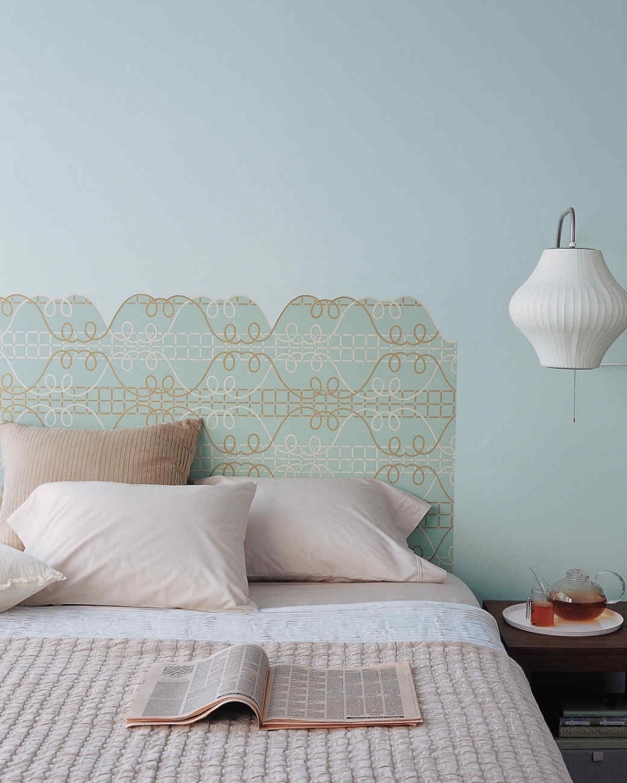 une tete de lit diy réalisée en papier peint imprimé motif vintage, découpée dans une forme imitant la structure d'une tête de lit en bois