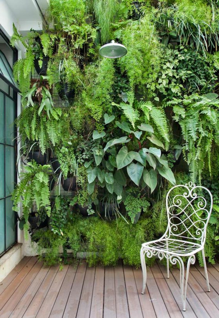 un grand mur végétal très vert, zone douche extérieure, chaise en métal blanc en style rétro, sol recouvert de poutres en bois marron clair, habiller un mur extéieur 