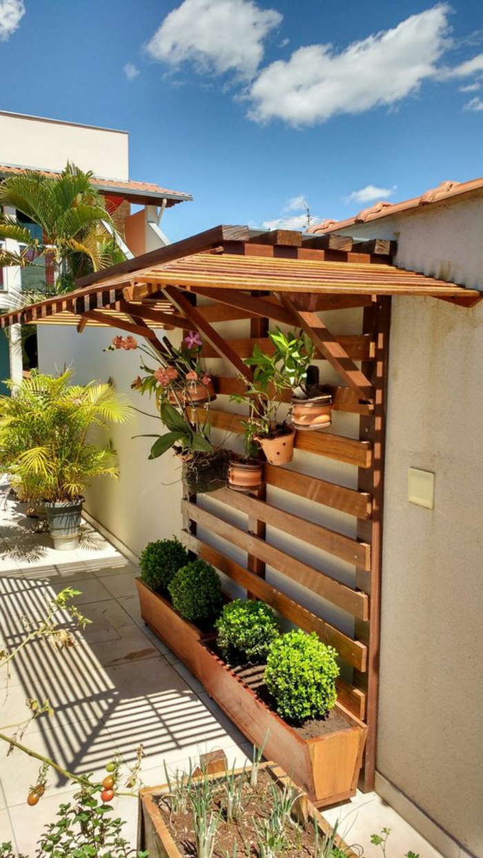 deco mur exterieur, coin pour un porte-plante original en bois beige, petit toit installé au-dessus des plantes, mur de jardin peint en couleur ivoire
