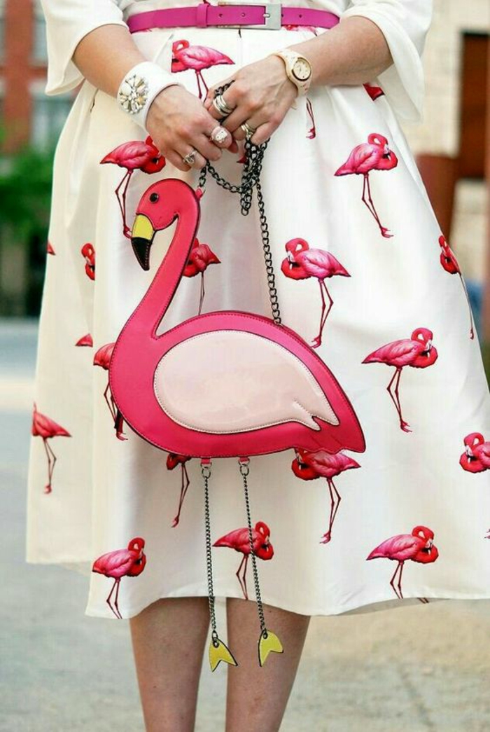mode féminine, blouse blanche et jupe fortement évasée blanche aux flamants roses, sac en forme de flamant rose avec chaînette métallique, objet deco original