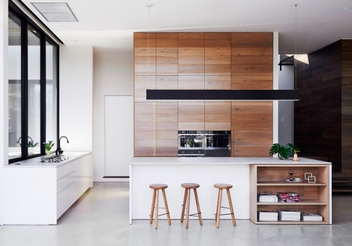 exemple design intérieur moderne dans une cuisine blanche avec pan de mur en bois brut et ilot central blanc et bois