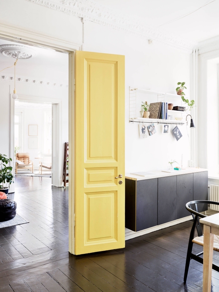 une porte d'intérieur repeinte en jaune citron pour créer un accent coloré dans l'ambiance minimaliste de cet appartement scandinave