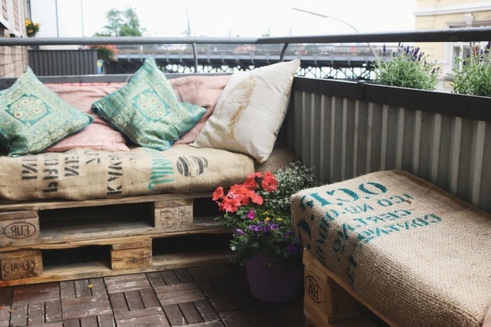 déco de style industriel sur le balcon avec plancher brut et mobilier banc et tabouret en palette fait main couverts de coussins