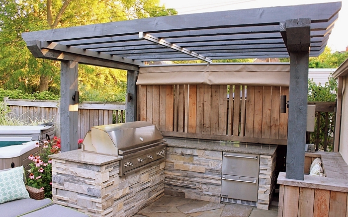idée pour aménager une cuisine d'extérieur avec toit de bois foncé et ilot en pierre, modèle de barbecue acier inoxydable